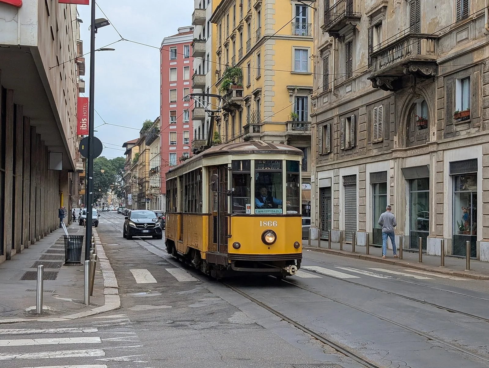 Tram storico giallo della serie 1500, detto Carrelli, in una via di Milano